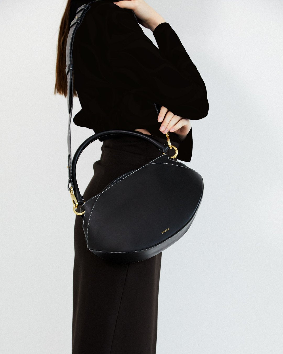 Sunrise Bag in Noir shown from a three-quarter angle showcasing its smooth black leather and gold hardware