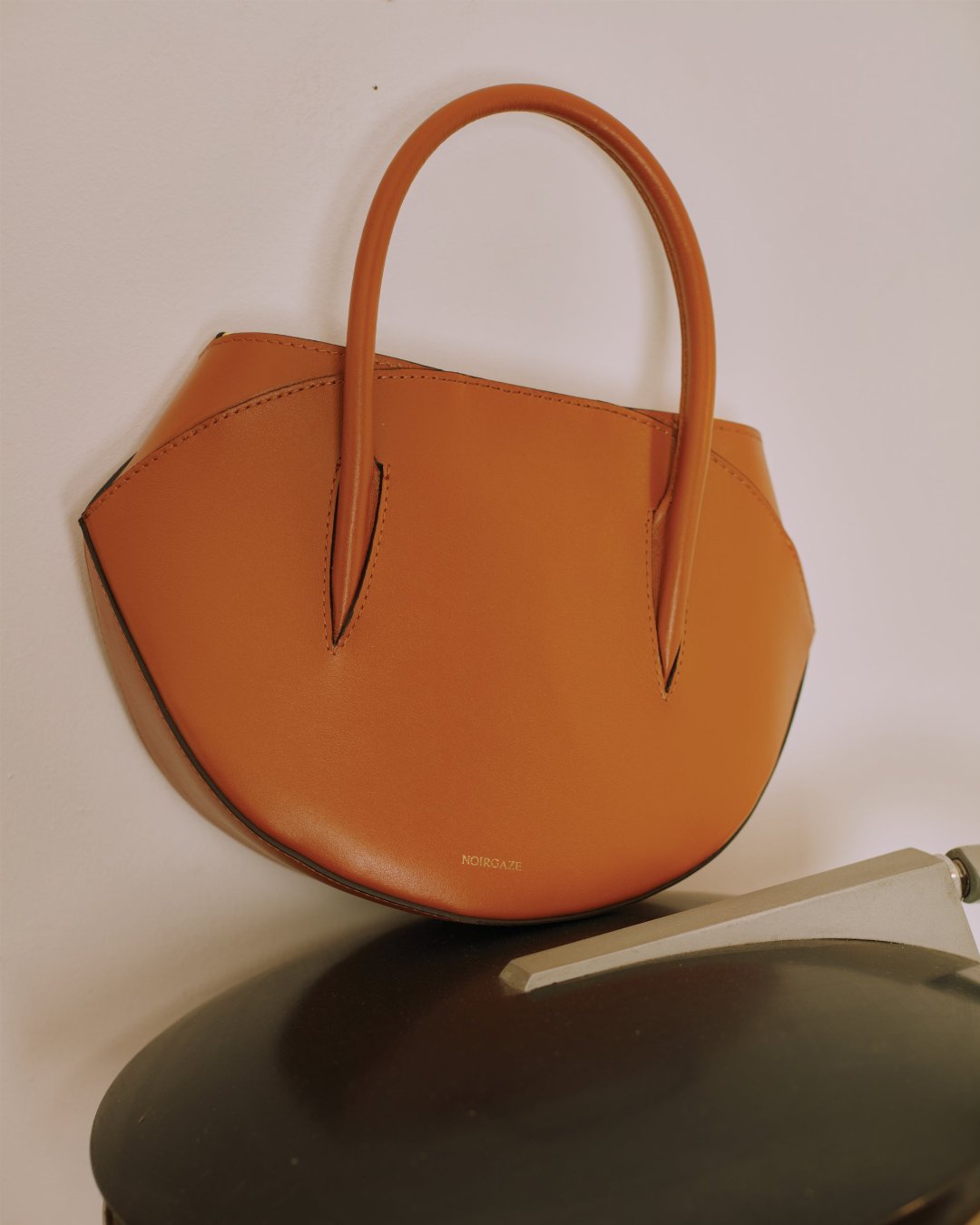Maggie Bag in Tan leather shown from a three-quarter angle showcasing its curved half-moon structure